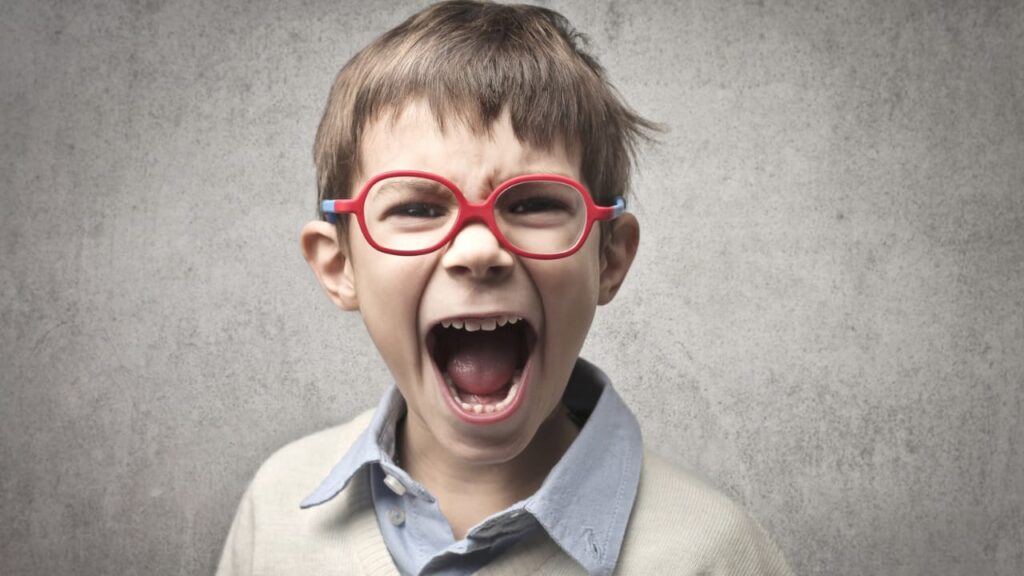 Menino de óculos gritando transtorno opositivo desafiador.
